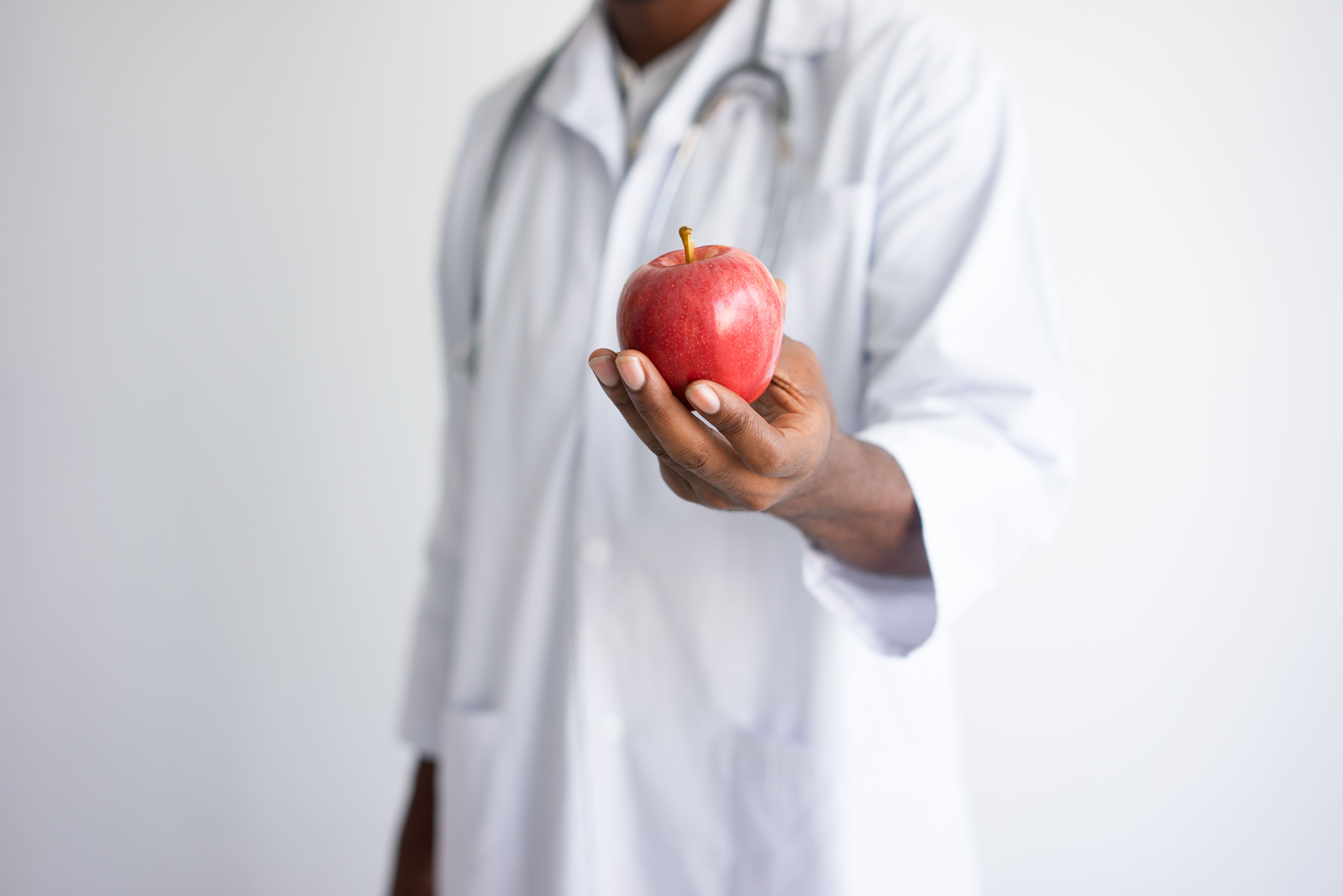 closeup-black-male-doctor-holding-offering-red-apple